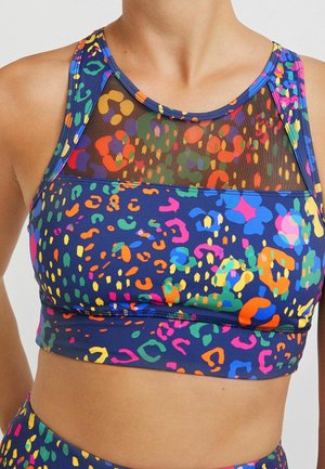 Kolorowy top sportowy z abstrakcyjnym, wielokolorowym nadrukiem w cętki lamparta oraz czarną siateczką na górnej części klatki piersiowej i ramionach.