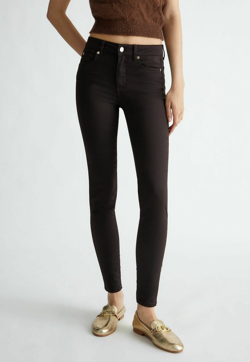 Zwarte skinny jeans met een gladde textuur, hoge taille en vijf zakken. Voorzien van zilveren beslag voor het sluiten aan de voorkant.
