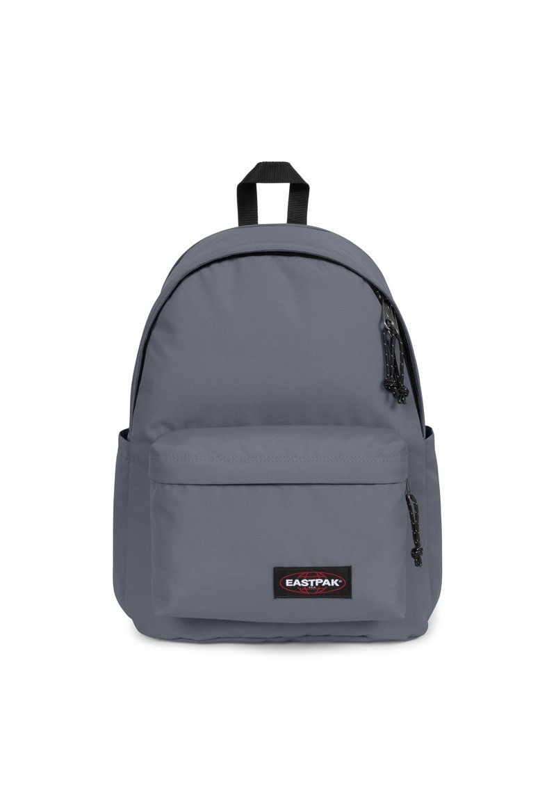 Mochila Eastpak gris con forma redondeada, cierres de cremallera, correas ajustables y un bolsillo frontal con una etiqueta de logo. Tejido duradero.