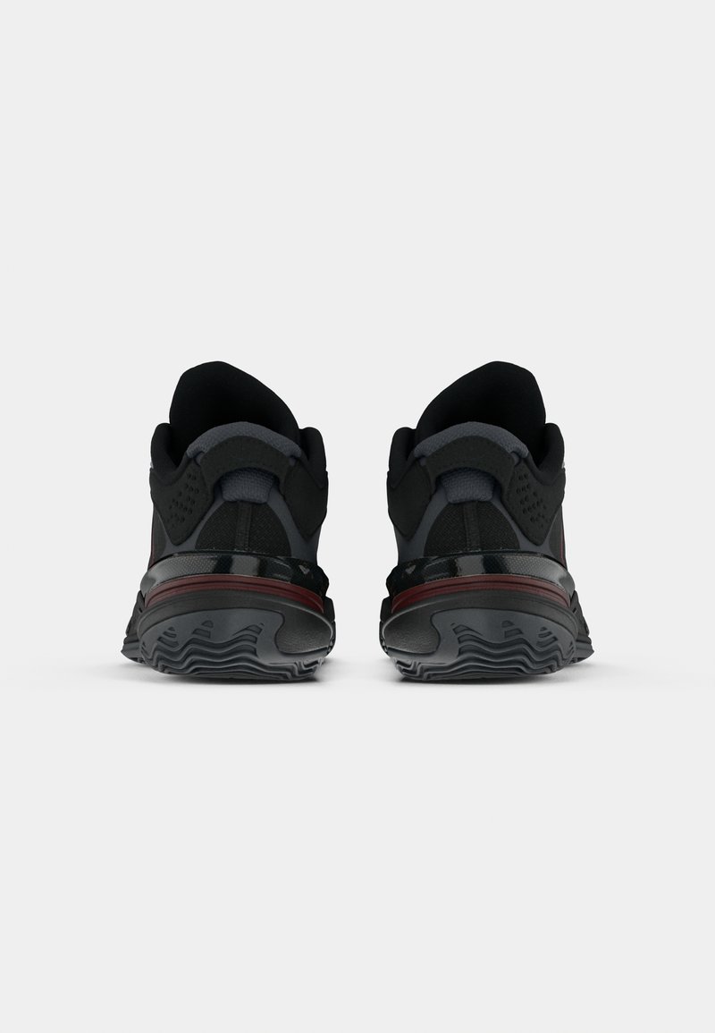 Scarpe sportive nere con tomaia in rete, collo imbottito, suola testurizzata e accenti rossi a contrasto sulla suola intermedia.
