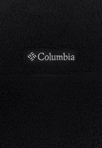 Sort fleece pullover med en blød, struktureret overflade. Har et rektangulært mærke med "Columbia" logo i sølvsyning på forsiden.