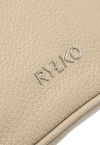 Borsa a mano in pelle beige con texture e finitura morbida, accentuata dal logo silver "RYŁKO". Presenta un design elegante e semplice.