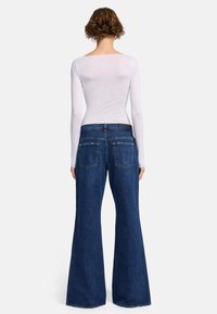 Jeans a vita alta svasati in denim blu scuro. Presentano un classico design a cinque tasche con una vita liscia e una leggera sfilacciatura all'orlo.