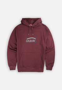 Sweat à capuche bordeaux en tissu doux, avec une poche frontale, une capuche à cordon de serrage et un design de logo avec des accents de feuille sur la poitrine.