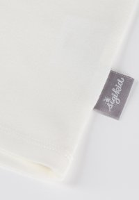 White cotton fabric with a soft texture and a stitched hem, featuring a gray fabric label with "styled" embroidered in light gray.