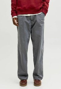 Grå bomuldsbukser med en løs pasform og lige snit, der har sidelommer. Båret med en rød sweatshirt og brune sko. Struktureret stof.