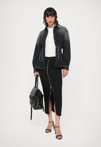 Chemise en denim gris foncé avec un bouton devant et une couture contrastante, accompagnée d'une jupe midi noire dotée d'une fermeture éclair dorée et d'une fente.