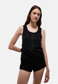 Débardeur sans manches noir avec un col rond et des d�étails texturés verticaux à l'avant, assorti avec un short noir.