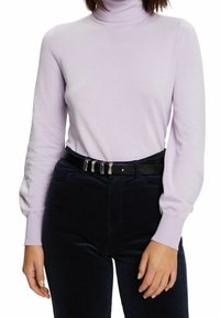 Lichtpaarse coltrui met lange mouwen, gecombineerd met donkere ribfluwelen broek en een zwarte riem met zilverkleurige accenten.