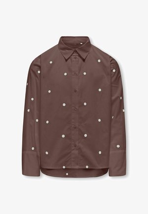 Chemise marron à manches longues avec boutons, parsemée de petits pois blancs, col pointu et manches retroussées.