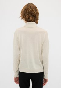 Crème trui met lange mouwen en een hoge hals, met een zachte textuur en parelversieringen langs de mouwen. Slim fit, casual ontwerp.