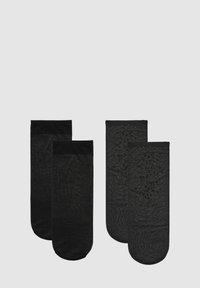 Calze nere, due stili: una con texture liscia e design uniforme, l'altra con un motivo a pois, entrambe con polsini elastici.