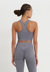 Grå sportbh och tights med strukturerade mönster. Racerback-design, åtsittande form och hög midja på tightsen.