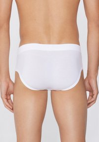 Bílé bavlněné slipy s hladkým povrchem a širokým elastickým pasem. Mají klasický střih a minimalistický design.