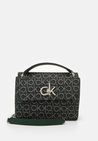 Mørkegrøn håndtaske med gentagen "ck" mønster, sølv "ck" logo lås, top-håndtag og aftagelig skulderrem.