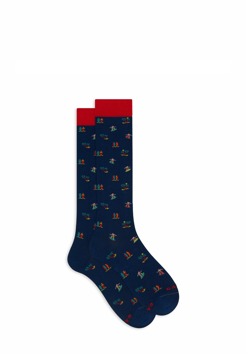 Marineblaue Socken mit lebendigen sommerlichen Mustern, darunter Palmen, Surfbretter und Strandelemente. Rote, gerippte Bündchen; glatte Strickstruktur.