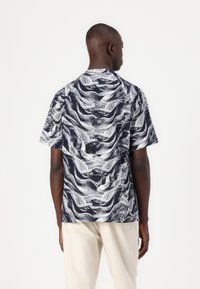 Short-sleeve shirt with a dark navy base and white wave pattern, featuring a straight cut and soft fabric texture.