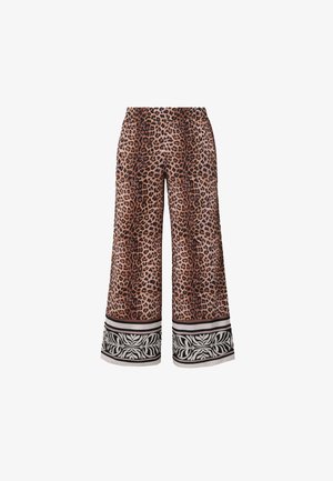Pantaloni a gamba larga con stampa leopardata marrone e nera e polsini con motivo floreale bianco e nero su sfondo bianco.
