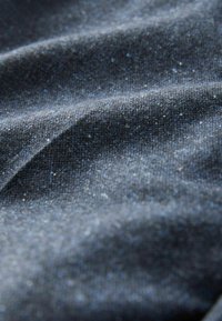 Dunkelblauer Stoff mit einem subtilen Glanz, der eine strukturierte Oberfläche und feine glitzernde Details aufweist. Glatter, fließender Fall.