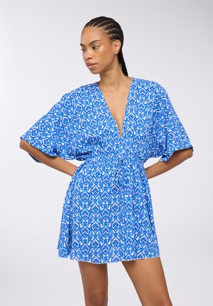 Abito blu con motivo a fantasia, scollatura a V profonda, maniche a batwing corte e vita elasticizzata, caratterizzato da intricati disegni floreali in diverse tonalità di blu.