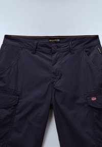 Pantalon cargo bleu marine foncé avec poches avant, poches à rabat latérales, passants de ceinture, fermeture par bouton et petit détail de drapeau sur la poche droite.