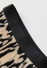 Tessuto plissettato in beige con motivi astratti neri, dotato di una cintura nera liscia. La texture è morbida con una leggera lucentezza.