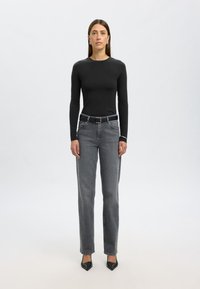 Juoda ilgarankovė palaidinė, prigludusi, derinama su aukštu liemeniu pilkomis tiesiomis džinsomis ir juodais smailiais aukštakulniais. Paprastas dizainas, be matomų raštų.