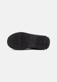 Semelle de chaussure en caoutchouc noir avec un motif texturé, présentant des rainures pour la traction et un design de bout arrondi. Style simple et fonctionnel.
