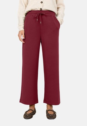 Burgundy wide-leg sweatpants with an elastic waistband, drawstring, side pockets, and smooth fabric texture. Pairing with dark, studded shoes.