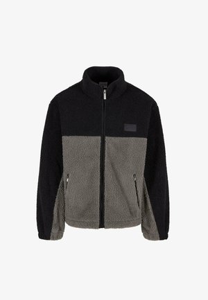 Fleece striukė su dviejų tonų dizainu, juodomis ir pilkomis panelėmis, užtrauktuku priekyje ir šoninėmis kišenėmis. Tekstūruota, minkšta medžiaga su aukštu apykakle.