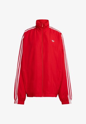 Rote Trainingsjacke aus glattem Material, mit hohem Kragen, Frontreißverschluss und weißen Streifen an den Ärmeln. Kleines Logo auf der Brust.