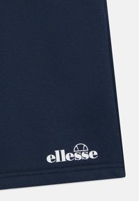 Námořnická modrá tričko vyrobené z bavlny, s bílým logem ellesse v dolním levém rohu, měkkou texturou a jednoduchým designem.