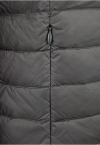 Sección de chaqueta acolchada gris con paneles acolchados, costuras horizontales, una textura suave y una cremallera central con un tirador.