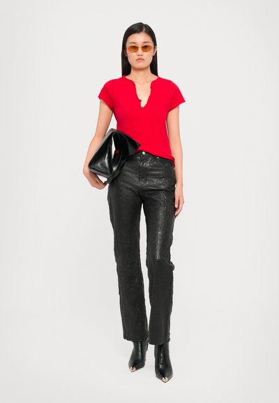 Red short-sleeved t-shirt with a keyhole neckline, paired with black textured leather pants and pointed black ankle boots. Black clutch under arm.