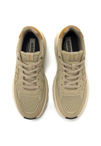 Zapatillas beige con una parte superior de malla texturizada, acentos sólidos y suelas de goma en tonos neutros. Presentan una punta redondeada y un diseño clásico de cordones.
