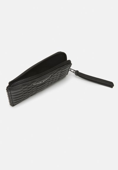 Portefeuille en cuir noir avec un design matelassé, fermeture à glissière et sangle pour le poignet. Présente une texture lisse et un matériel minimal.