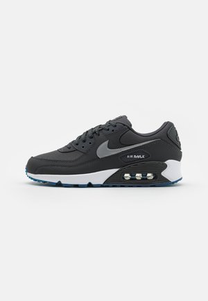 Sort og grå Nike Air Max sneaker med hvid midtersål, synlig luftpolstring og blå ydersål, vist fra ydersiden på en hvid baggrund.