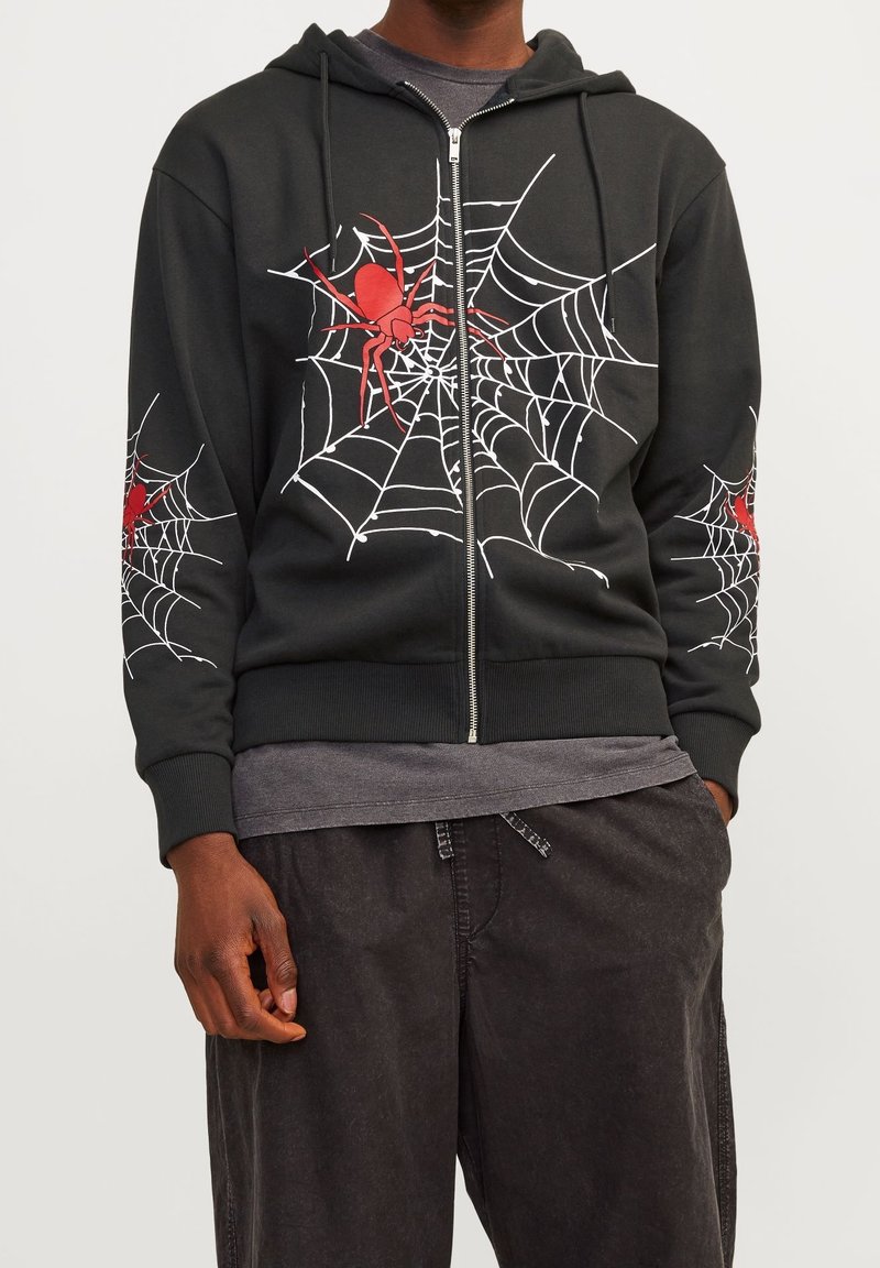 Sudadera negra con cremallera que presenta gráficos de una araña roja y una telaraña en el frontal y las mangas. Está hecha de una tela suave con puños y cinturilla acanalados.
