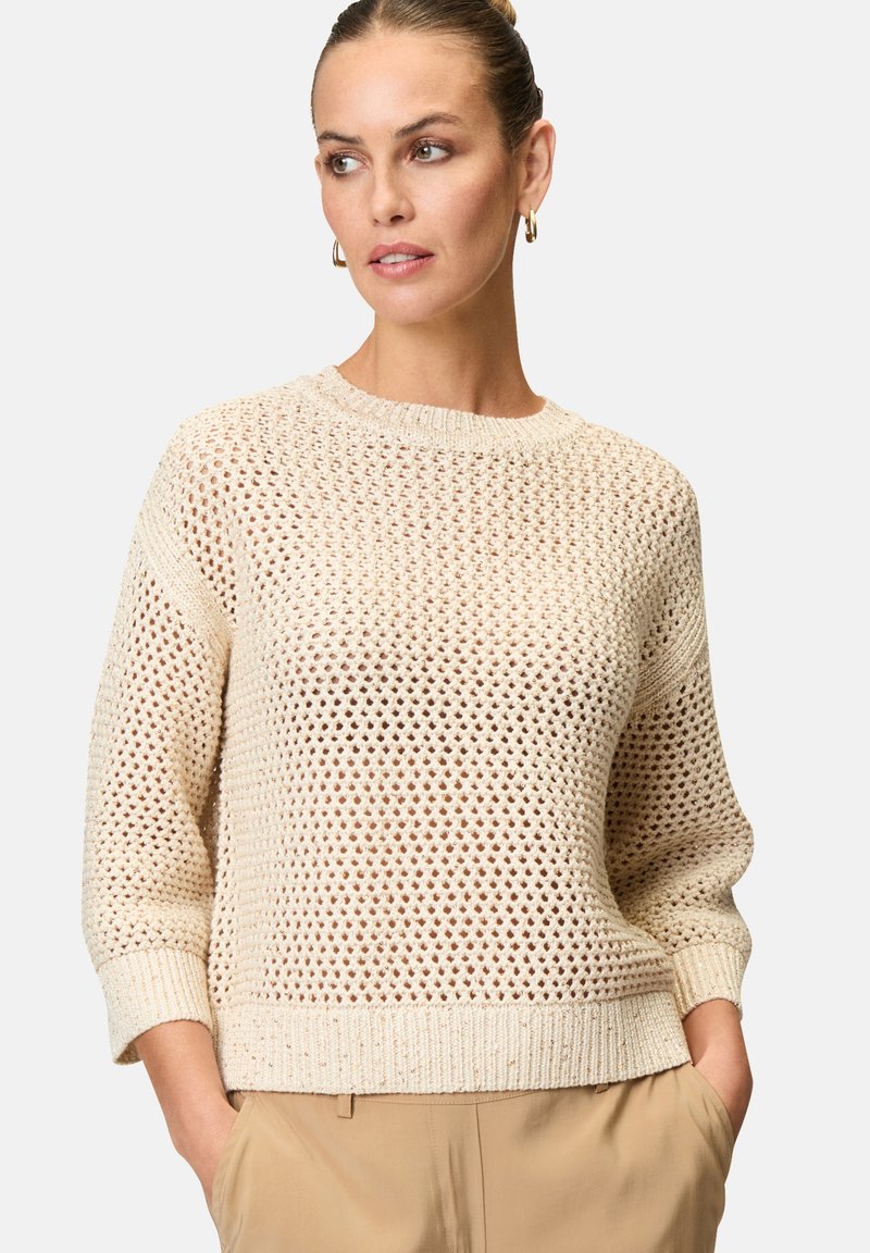 Knit sweater in light beige with a loose weave, ribbed neckline, and cuffs. Features three-quarter sleeves and a relaxed fit.