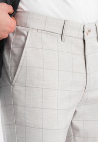 Pantaloni grigi chiari su misura con un fine motivo a reticolo, caratterizzati da una texture liscia, tasche laterali e un design slim fit.