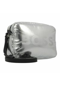 Zilveren puffer crossbody tas met een gladde, glanzende buitenkant, een verstelbare zwarte schouderband en een reliëf "BOSS" logo aan de voorkant.