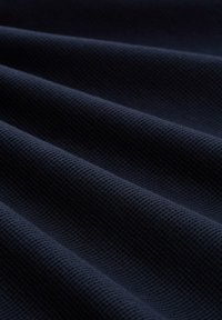 Donker marineblauwe stof met een gestructureerde, ribbelachtige weving, met zachte, golvende plooien die het materiaal en de diepte accentueren.