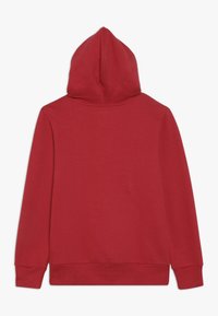 Felpa rossa con cappuccio dalla texture liscia. Presenta maniche lunghe, polsini a coste e una classica tasca a marsupio sul davanti.