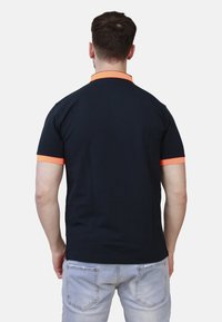 Polo shirt blu navy con colletto e maniche arancioni, realizzato in cotone; presenta una vestibilità classica e un design a tinta unita.