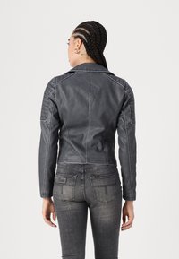 Grå skinnjakke med en tettsittende design, som har skulderpolstring, ribbede detaljer og en kort krage. Bærers over mørke jeans.