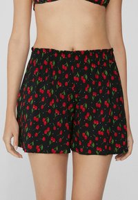 Černé šortky s motivem třešní, červené třešně a zelené listy, elastický pas a volný střih. Lehká tkanina.