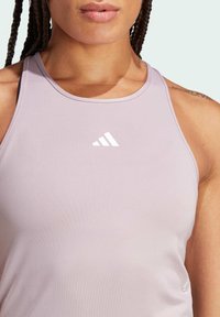 Canottiera atletica lavanda realizzata in tessuto flessibile, con scollatura rotonda e logo bianco sul petto. Texture morbida e liscia.