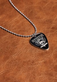 Collar de cadena de bola plateada con un colgante de pua de guitarra negra que presenta un logo de escorpión y el texto "SCORPIONS EST. 1965." sobre una superficie marrón texturizada.