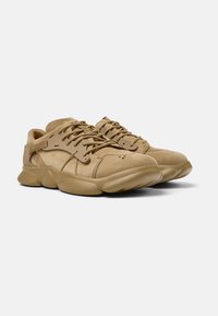 Sneakers in suede beige con colletto imbottito, chiusura con lacci, suola in gomma testurizzata e un branding discreto sul lato. Design con punta arrotondata.