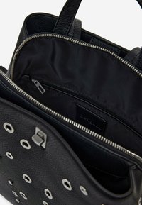 Black leather handbag with silver eyelet accents, zip closure, and textured surface. Features a black nylon interior and an internal zip pocket.